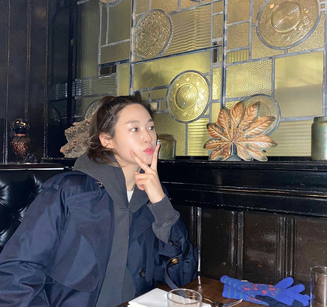 她是zico的前女友，深蓝风衣内搭灰卫衣出镜，身材依旧没的说